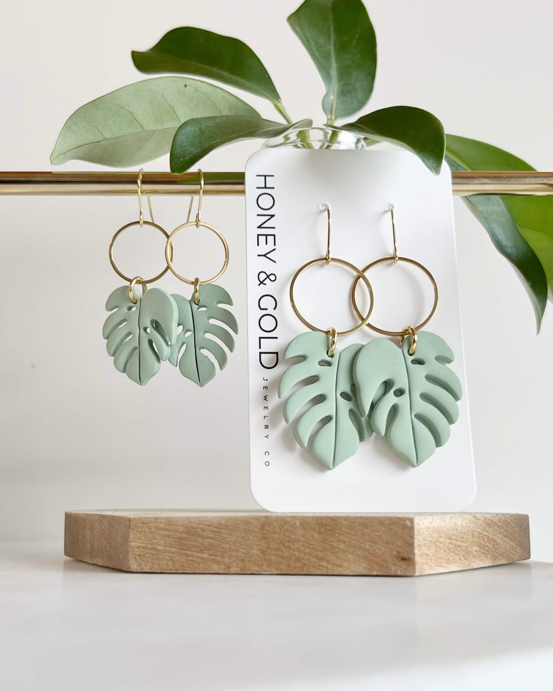 Green leaf-shaped earrings on a Honey & Gold branded card with leaves in the background