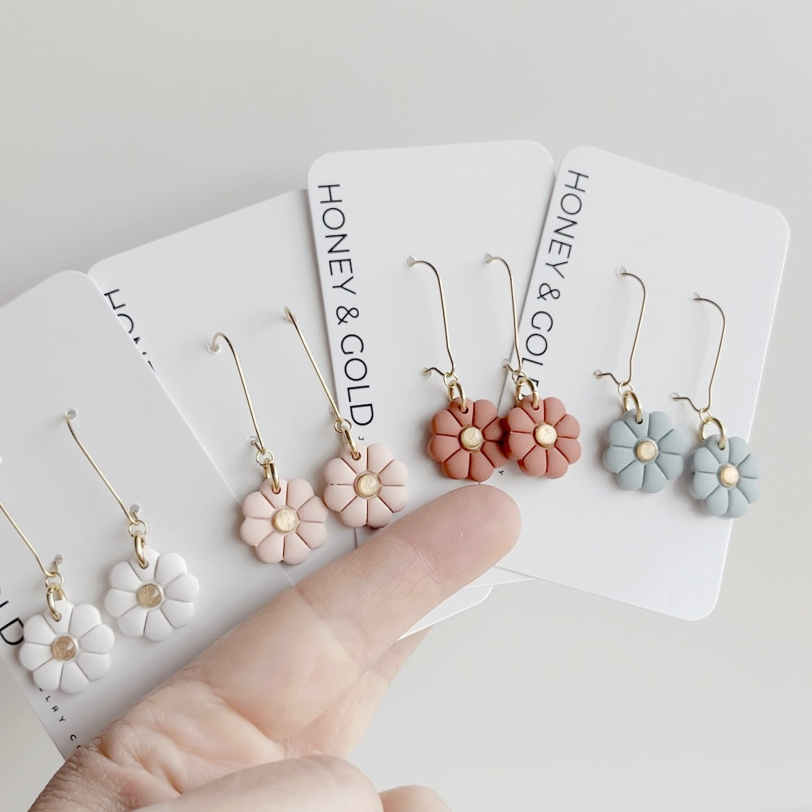 Floral earrings held up to a white background 